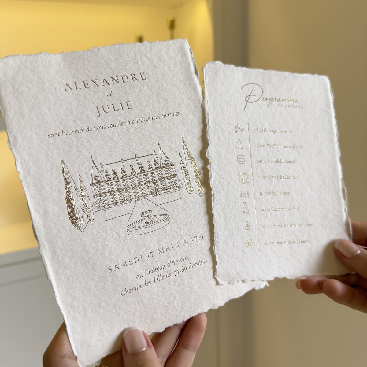 Détail d'une invitation de mariage avec illustration de château et programme assorti sur papier artisanal aux bords frangés
